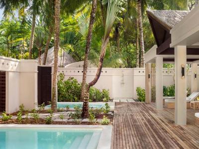 Espace extérieur moderne avec piscine, terrasse en bois et plantes tropicales dans un hôtel.