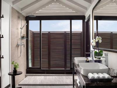 Nowoczesna łazienka z dużym prysznicem i naturalnym światłem w ciepłych barwach.