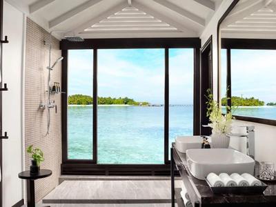 Jasna łazienka z dużym oknem i widokiem na błękitne morze oraz zielone wyspy.