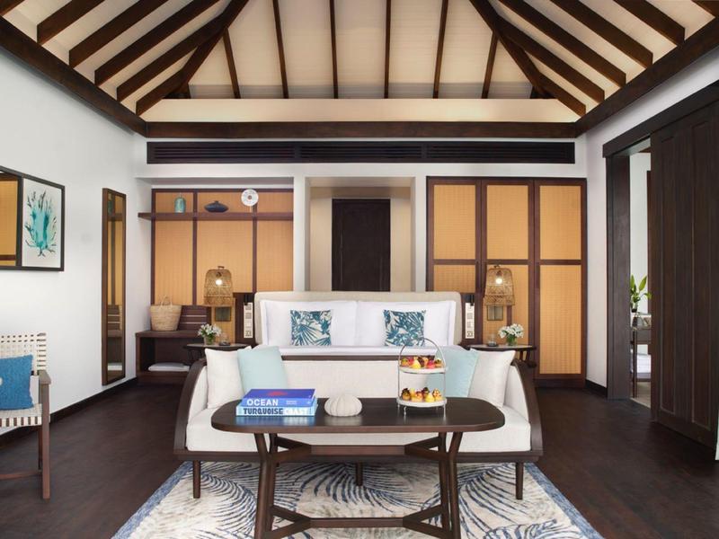 Elegancki salon z wysokim drewnianym sufitem, nowoczesnymi meblami i dużymi oknami.