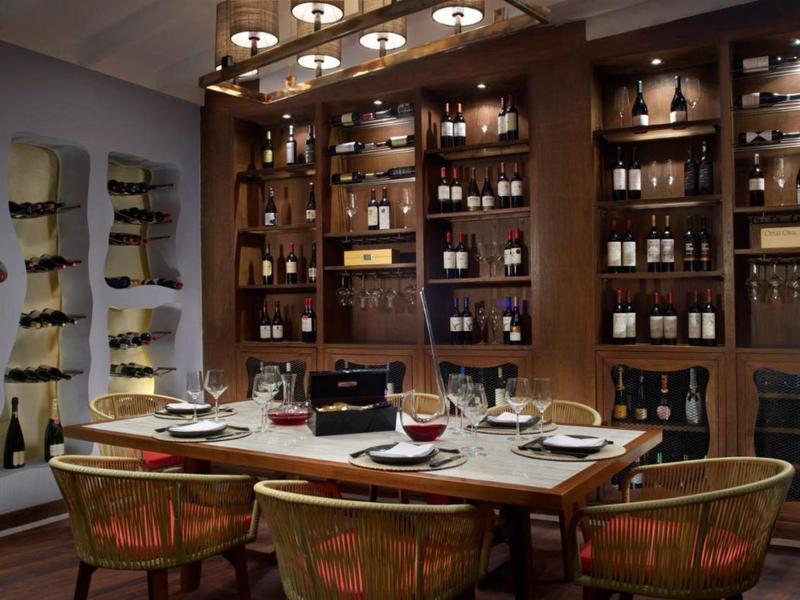 Elegancka sala do degustacji wina z drewnianymi meblami i butelkami na ścianach.