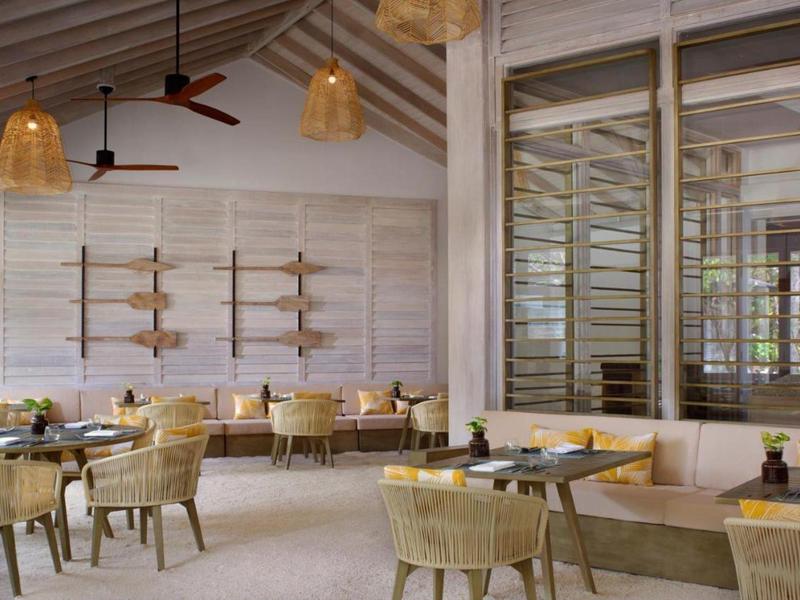 Jasna restauracja z drewnianym sufitem, krzesłami z rattanu i przytulnymi miejscami do siedzenia.