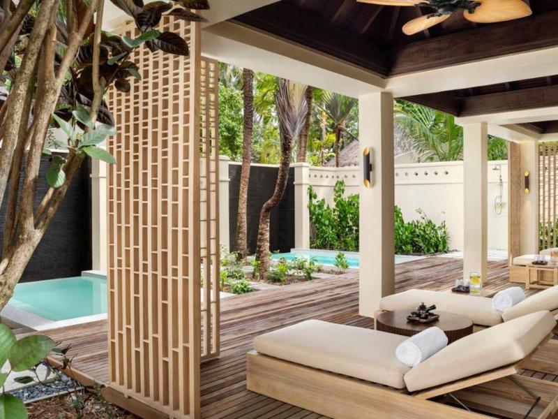 Nowoczesny taras z drewnianą podłogą, leżakami i basenem w hotelowym ogrodzie.