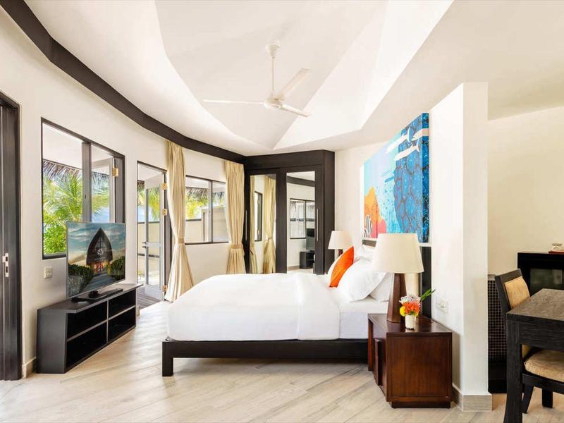 Moderne hotelkamer met grote ramen, wit beddengoed en een nachtkastje met lamp.