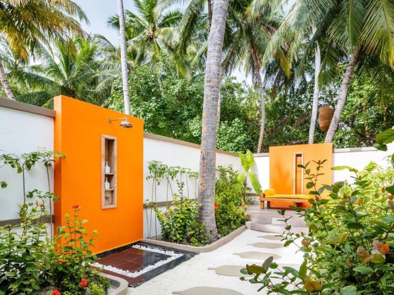Buitenruimte met feloranje muren, palmbomen en tropisch groen.