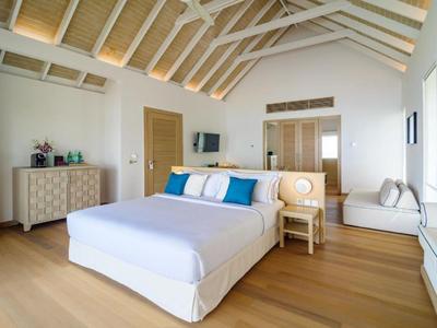 Helles Schlafzimmer mit Holzboden, großem Bett, weißer Kommode und eingebautem Fensterbereich.