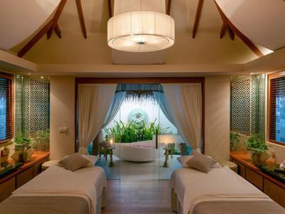 Luxurious spa room with two massage tables, large bathtub, and ambient lighting.