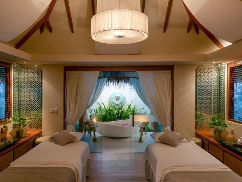 Luxurious spa room with two massage tables, large bathtub, and ambient lighting.