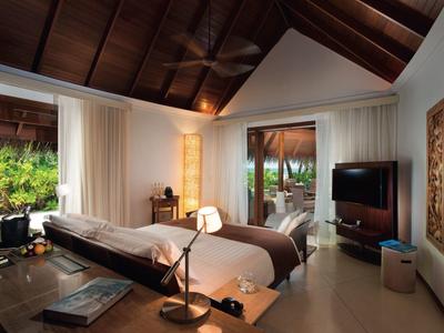 Camera d'hotel moderna con soffitto in legno, letto matrimoniale e vista sul giardino.