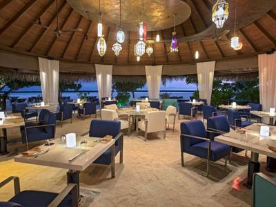 Area pranzo coperta aperta con mobili moderni e vista sul mare al crepuscolo.