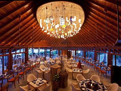 Ampio ristorante con soffitto in legno e lampadario centrale, arredato con stile per gli ospiti.