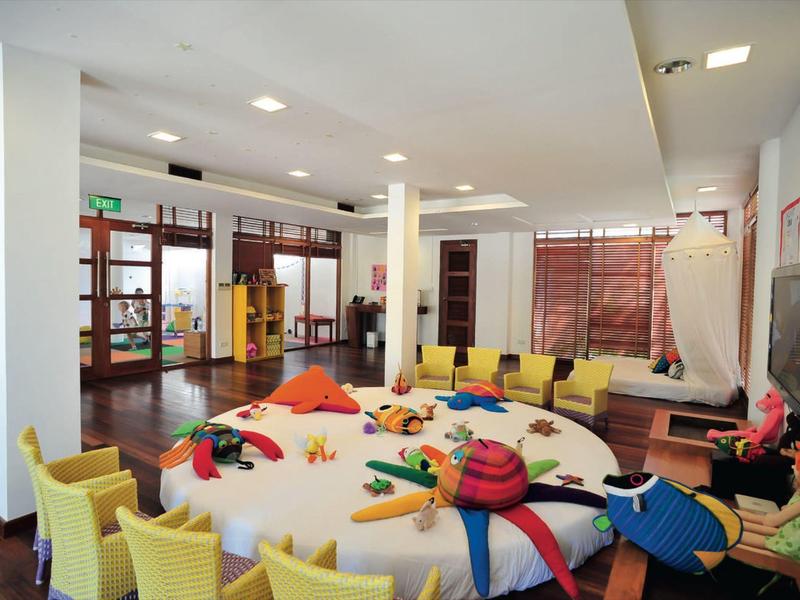 Ampia area con poltrone gialle attorno a un tavolo rotondo con cuscini colorati