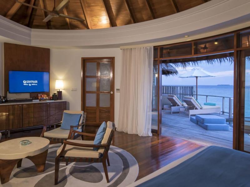 Camera d'hotel accogliente con balcone aperto e vista mare al tramonto.