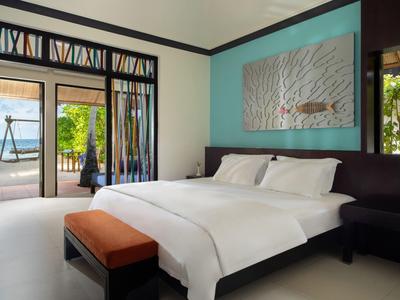 Modern hotel room with a large bed, ocean view, and blue walls.