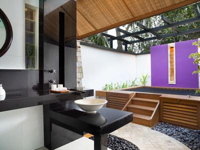 Modern outdoor bathroom with black sink counter, wooden ceiling, steps, and purple entry door.