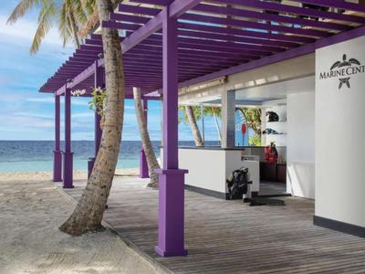 Centro sulla spiaggia aperto con pergolato in legno viola e vista mare sotto un cielo limpido