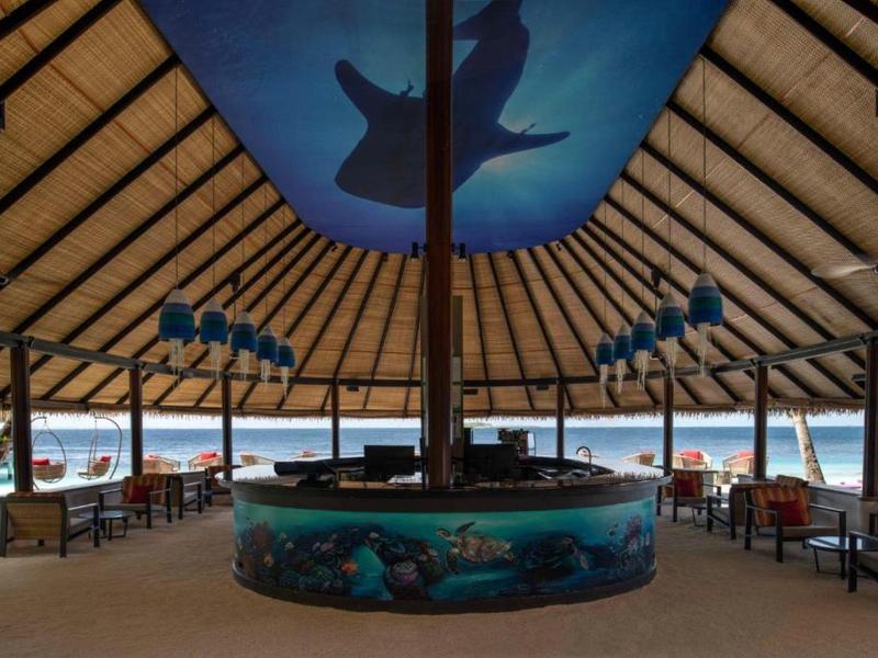 Open-air resort dining area with ocean view and a shark painted on the ceiling.