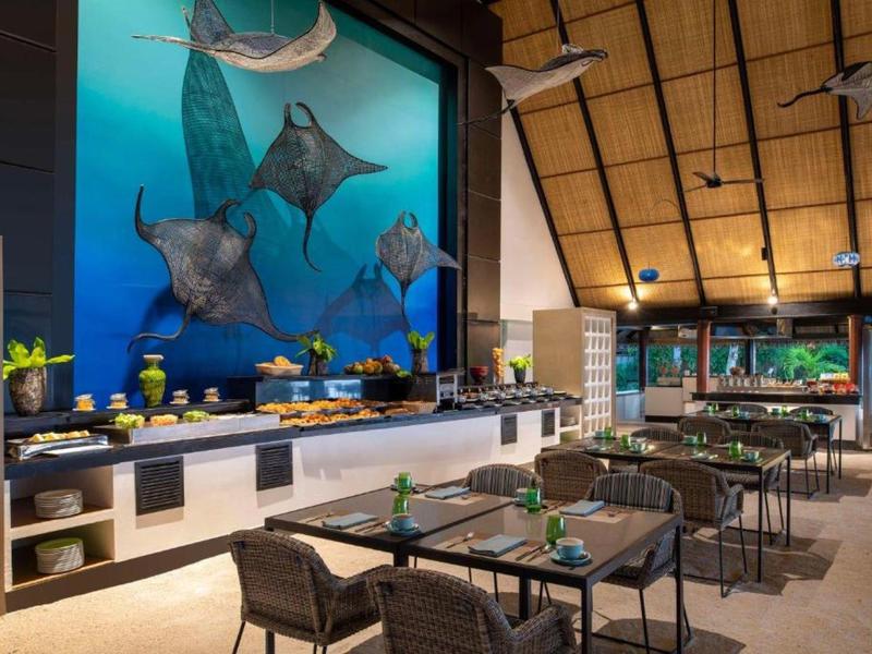 Hotel dining area with tables, chairs, buffet counter, and large marine life mural on the wall.