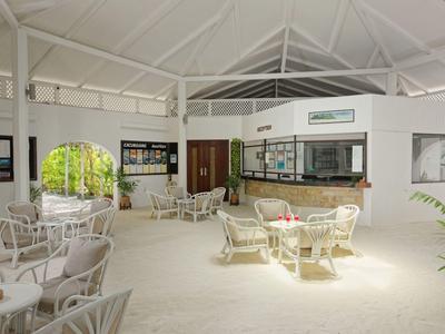 Area lounge luminosa e aperta con mobili in vimini bianchi e soffitti alti in un hotel.