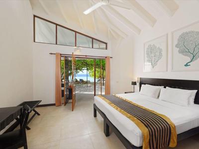 Světý hotelový pokoj s manželskou postelí, výhledem na tropickou zahradu a klidnou atmosférou.