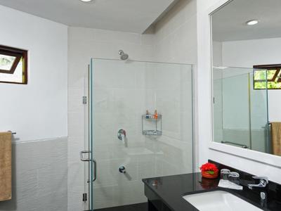 Moderní koupelna se sprchovým koutem ze skla, černou pracovní deskou a velkým zrcadlem.