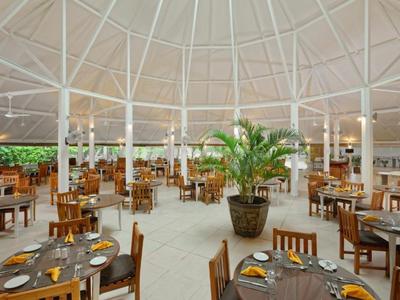 Ampia area ristorante aperta con tavoli e sedie in legno sotto una volta bianca a cupola.