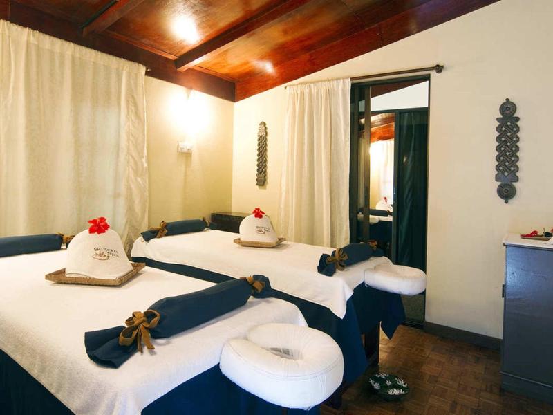 Elegantní masážní místnost se dvěma stoly, tlumeným osvětlením a teplou výzdobou.