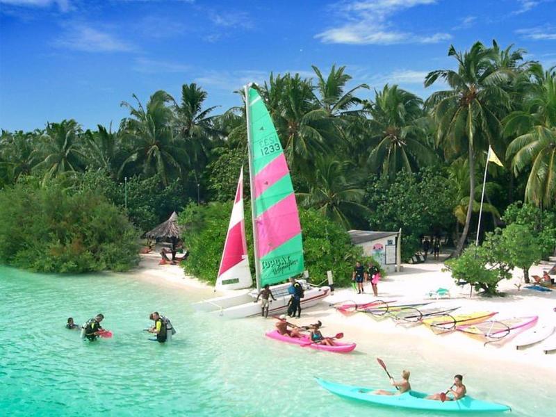 Pláž s bílým pískem, palmami, barevnými plachetnicemi a tyrkysovou vodou