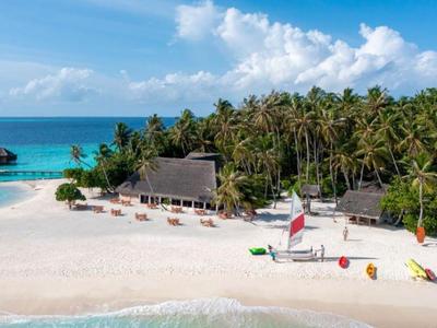 Spiaggia di sabbia bianca con una torretta di salvataggio e palme davanti a un mare turchese.