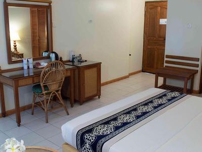 Jednoduchý hotelový pokoj se dvěma postelemi, psacím stolem, židlí a zrcadlem.