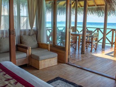 Pohodlný pokoj s dřevěným interiérem a výhledem na moře z terasy s posezením