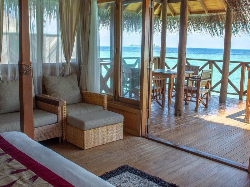 Pohodlný pokoj s dřevěným interiérem a výhledem na moře z terasy s posezením