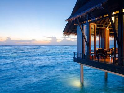 Vista di un ristorante sull'acqua al tramonto con mare calmo.