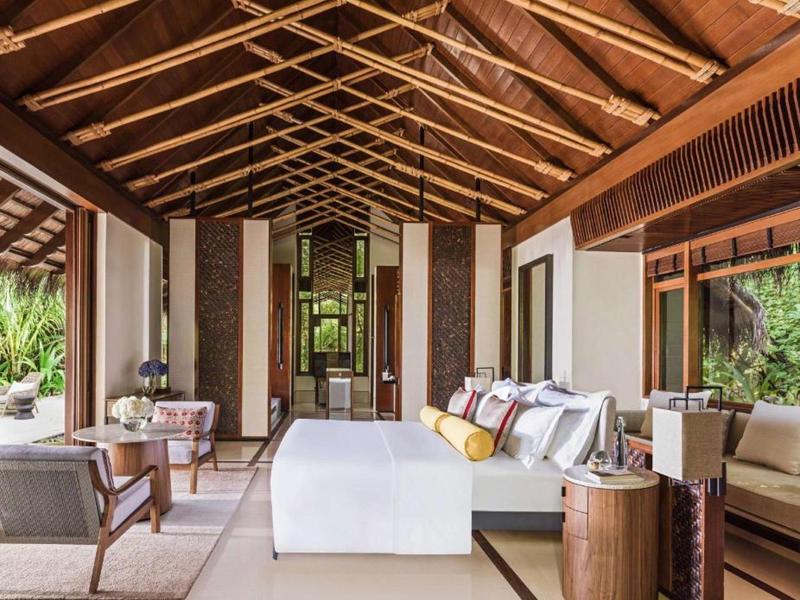 Spacious open-air hotel suite with wooden ceiling, comfy seating, and tropical views.
