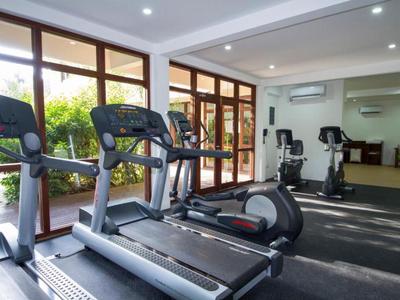 Helles Fitnessstudio mit Laufbändern und Blick auf einen Garten durch große Fenster.