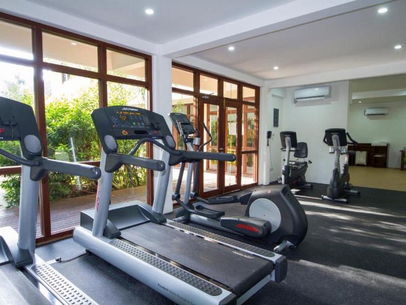 Moderne Fitnessstudio mit Laufbändern, Ergometern, großen Fenstern und heller Beleuchtung.