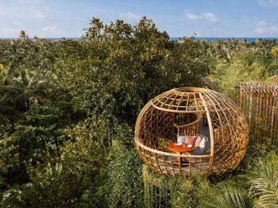 Otwarta, drewniana, okrągła platforma do wypoczynku wśród tropikalnych roślin i drzew.