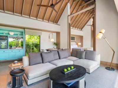 Jasny salon z szarą sofą, designerską lampą i dużą niebieską szafą przy oknach.