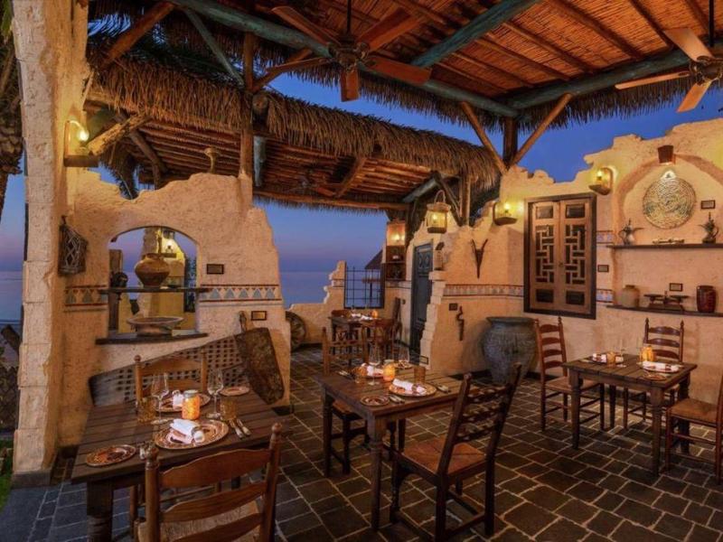 Przytulny, otwarty taras z kominkiem i widokiem na morze o zachodzie słońca.