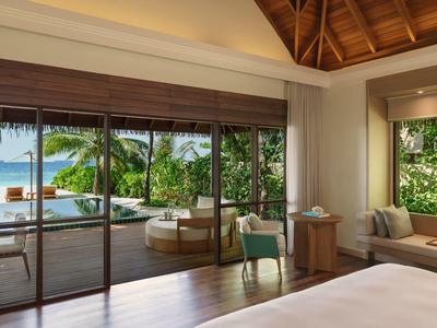Chambre d'hôtel moderne avec vue sur terrasse, piscine et végétation tropicale.