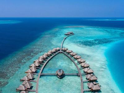 Überwasserbungalows in tropischem Hotelresort an klarem türkisfarbenem Meer