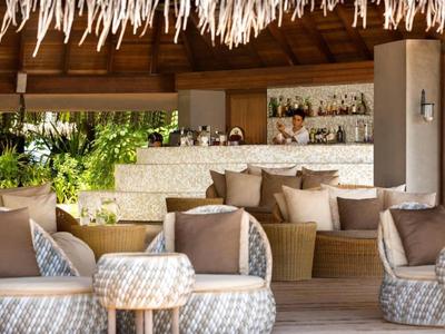 Espace lounge confortable avec fauteuils moelleux et bar dans un cadre ouvert et naturel.