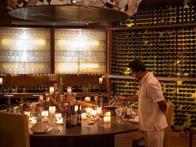 Cave à vin chaleureuse et luxueuse avec une table ronde élégamment dressée et un serveur.