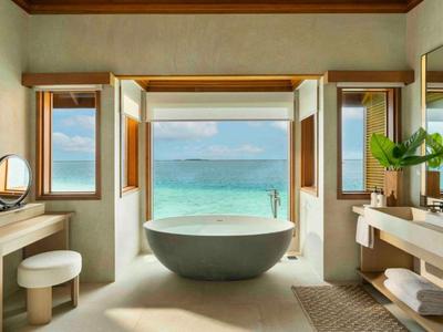 Salle de bains de luxe avec baignoire indépendante et vue sur la mer à travers de grandes fenêtres.