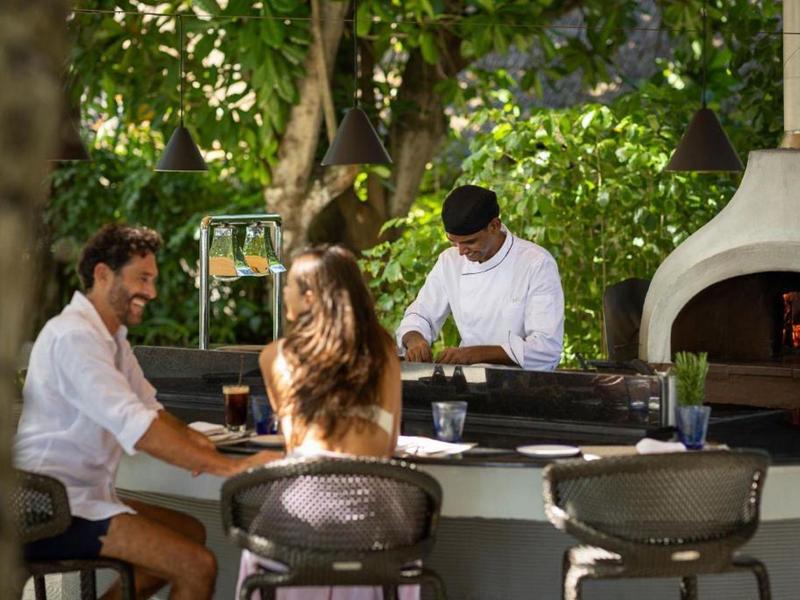 Couple profitant de boissons à un bar en plein air avec un barman et un grill en arrière-plan.