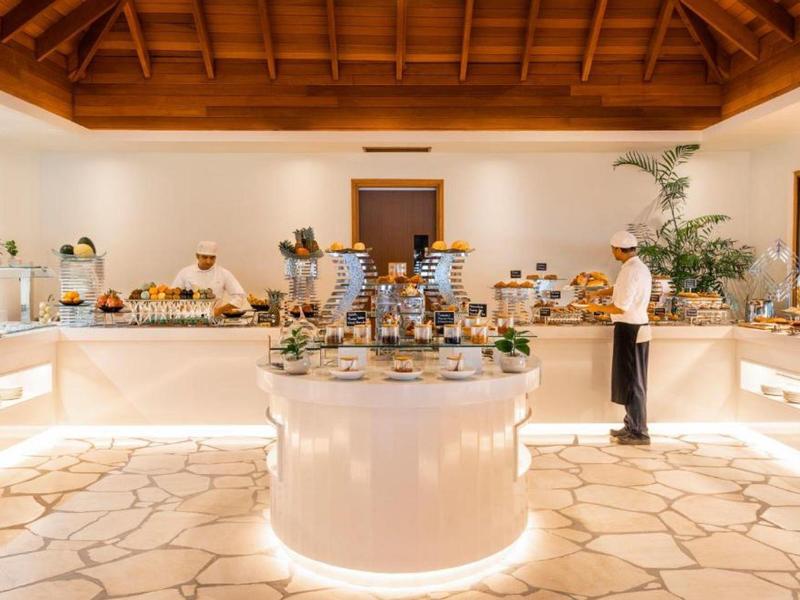 Une salle de petit-déjeuner lumineuse avec buffet et une personne choisissant de la nourriture.