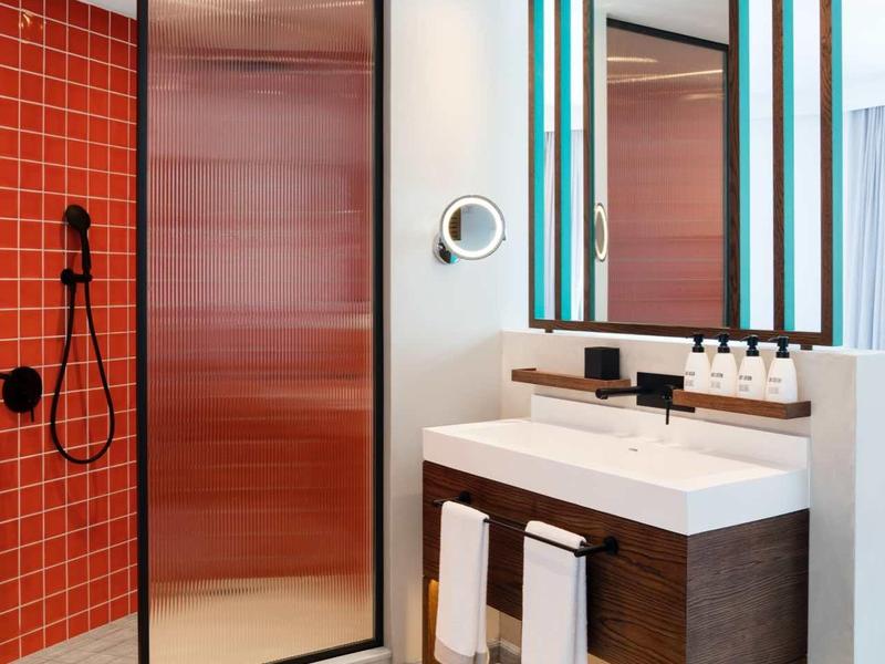 Modernes Badezimmer mit roter Fliesenwand, großer Spiegel und Doppelwaschbecken