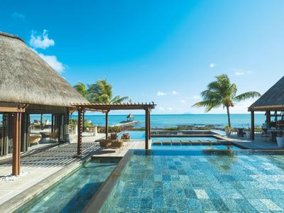 Luxuriöses Resort mit Pool, Blick auf das Meer und Palmen unter blauem Himmel