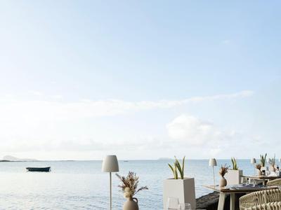Terrassentische mit Stühlen und Dekoration am Wasser bei klarem Himmel