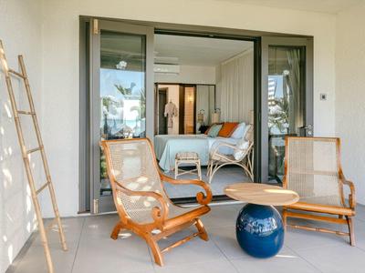Moderner Balkon mit Holzstühlen, rundem Tisch und Blick ins helle Schlafzimmer mit Balkonzugang.
